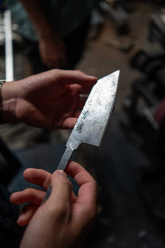 Hender holder et blad med navnet skrevet på, før skaftet er satt på.