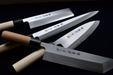 Finished single-bevel knives with wooden handles.
