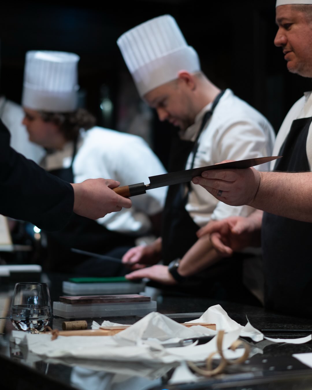 Kokker i kokkehue sliper kniver på våtstein