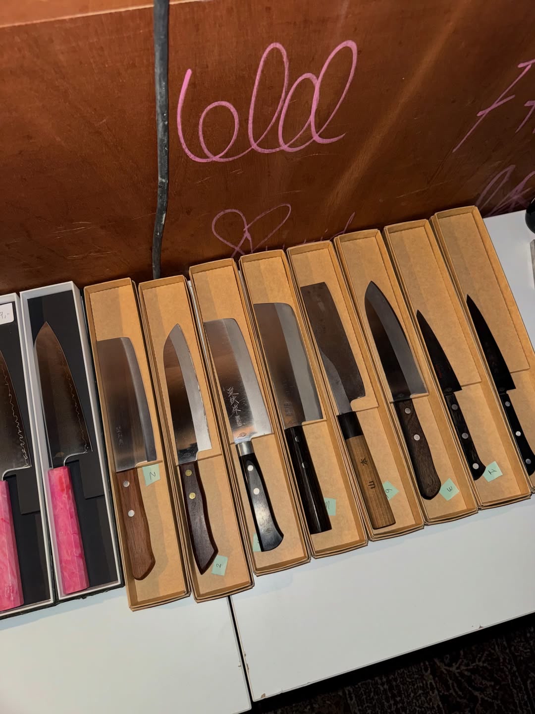 Brukte japanske kniver i nummererte pappesker på et bord