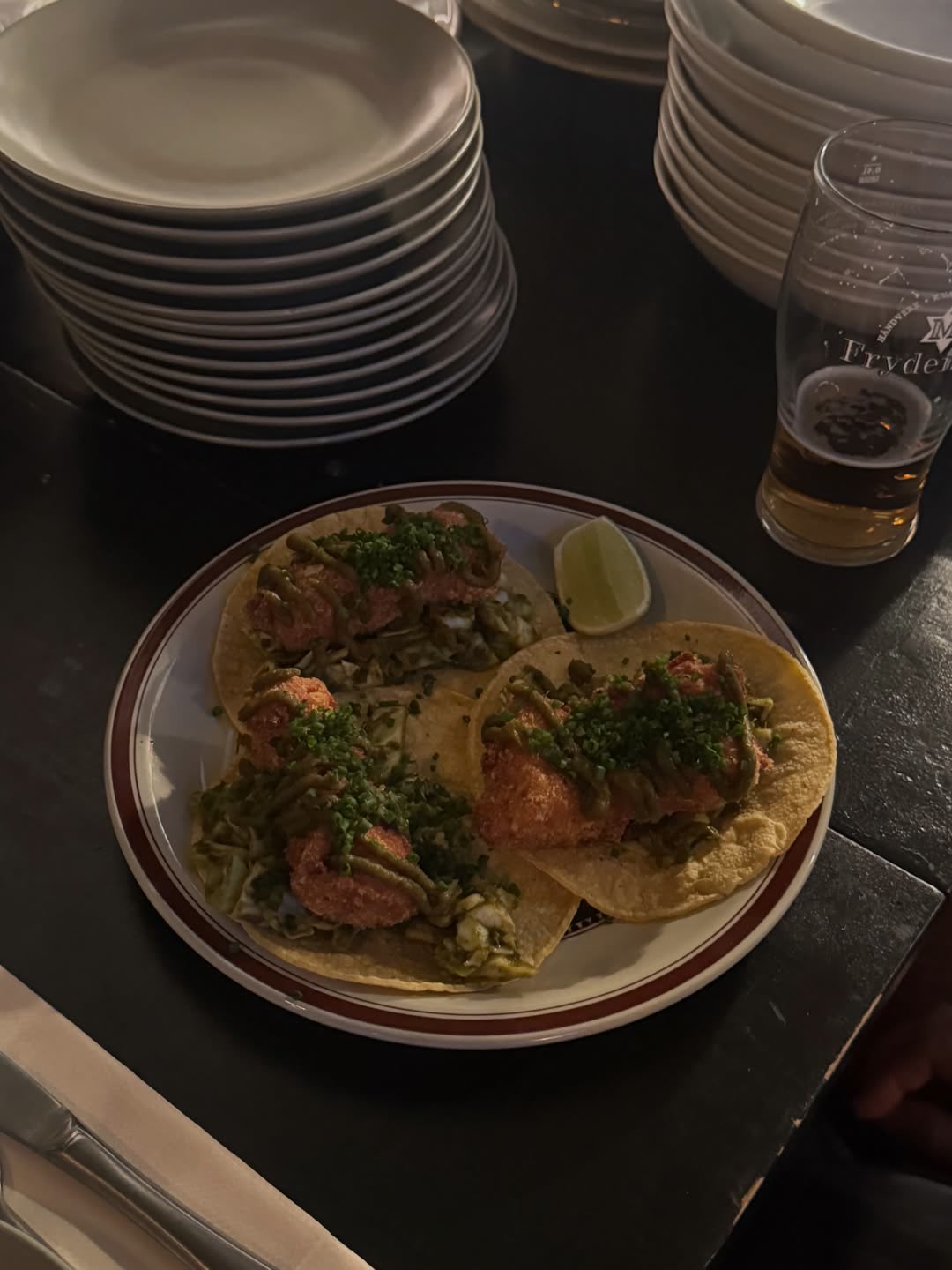 Tacos med lime og et glass øl på bordet i baren